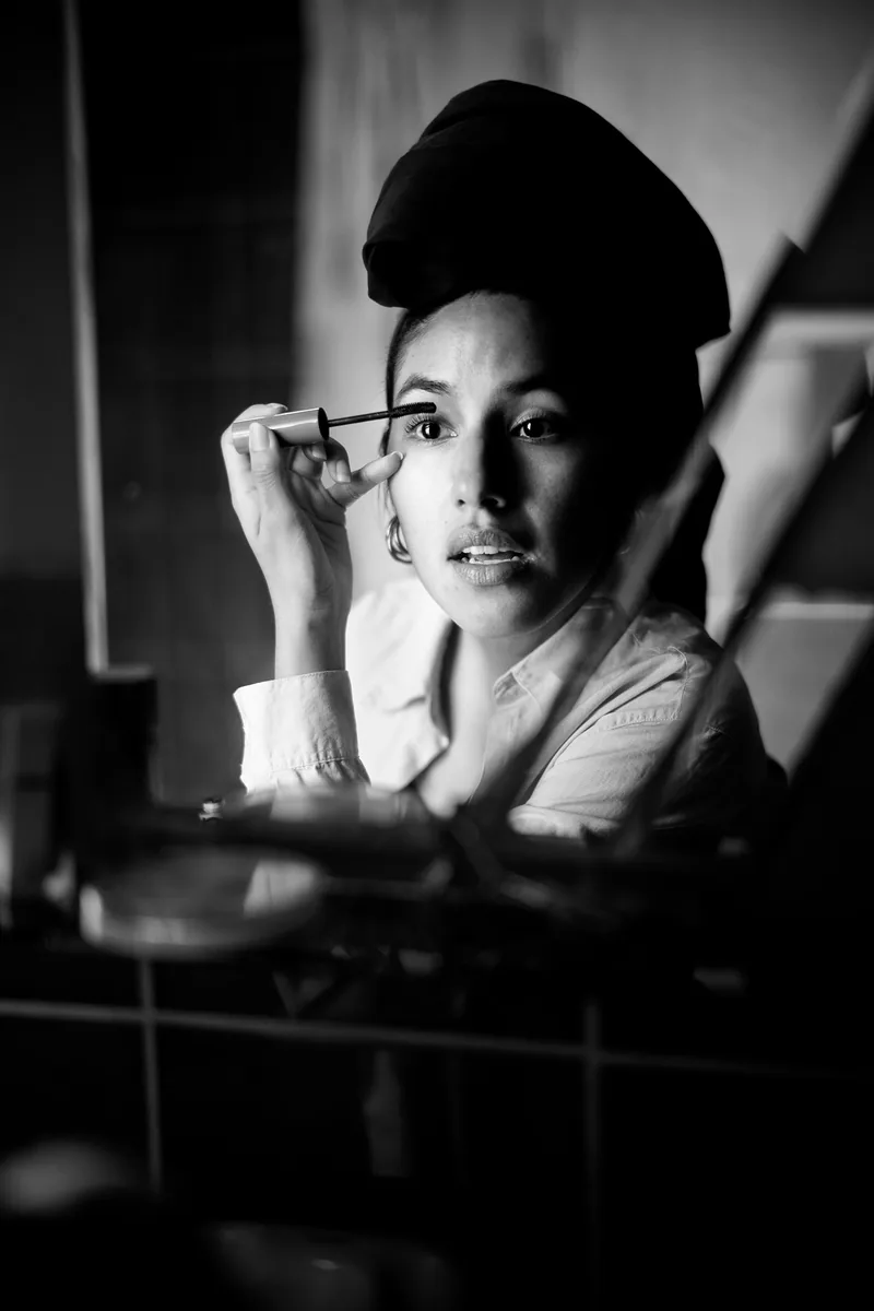 Mujer con boina maquillándose, retrato espontáneo en blanco y negro