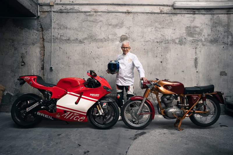 Retrato editorial de un hombre entre dos motos de carreras