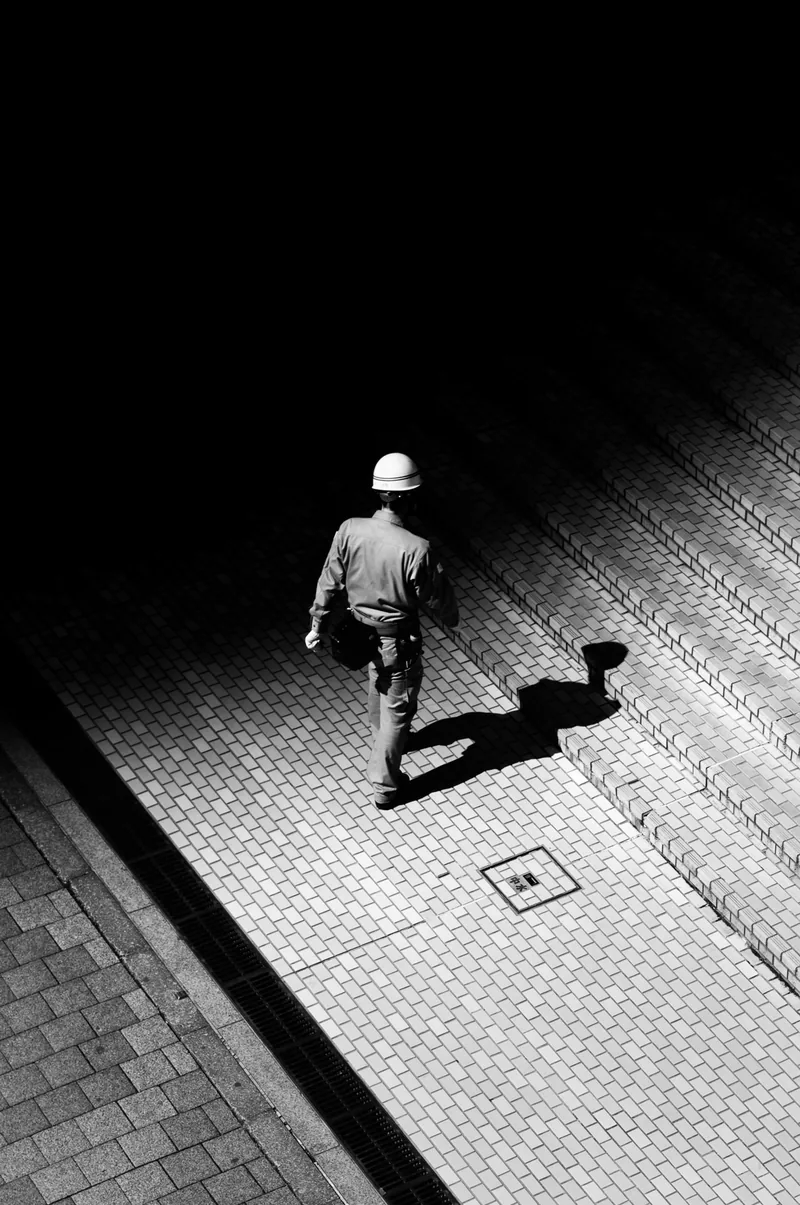 Passer-by and his shadow on a high-contrast pavement